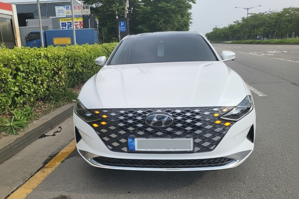 흰 색 세 단이 도로 옆 에 주차되어 있고, 노 란색 방향 지 시등이 켜져 있는 모습